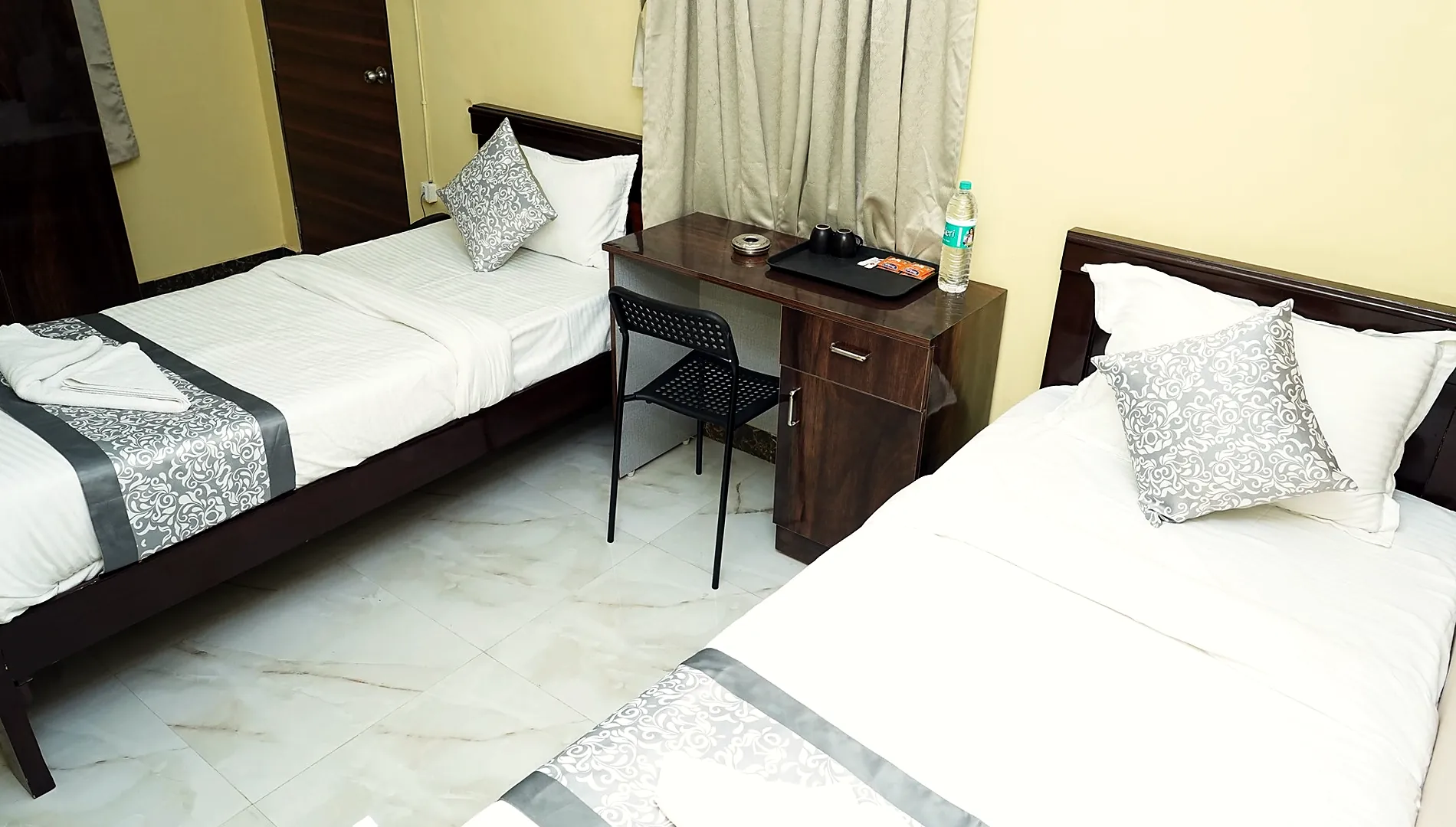 Guest room with two single beds and a work desk at Hotel Hyderabad Pulse